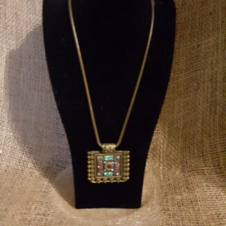 A necklace is displayed on a black stand.