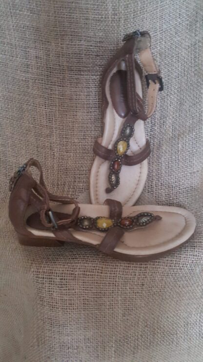 A pair of brown sandals sitting on top of a couch.