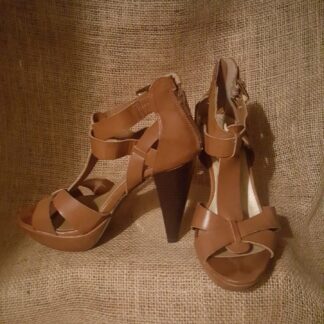 A pair of brown shoes sitting on top of a tan couch.
