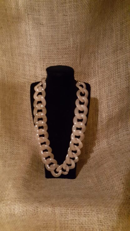 A necklace is displayed on the black mannequin.