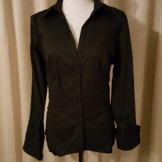 A black shirt is on display in front of a curtain.