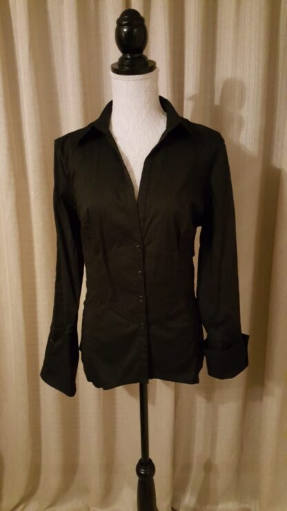 A black shirt is on display in front of a curtain.