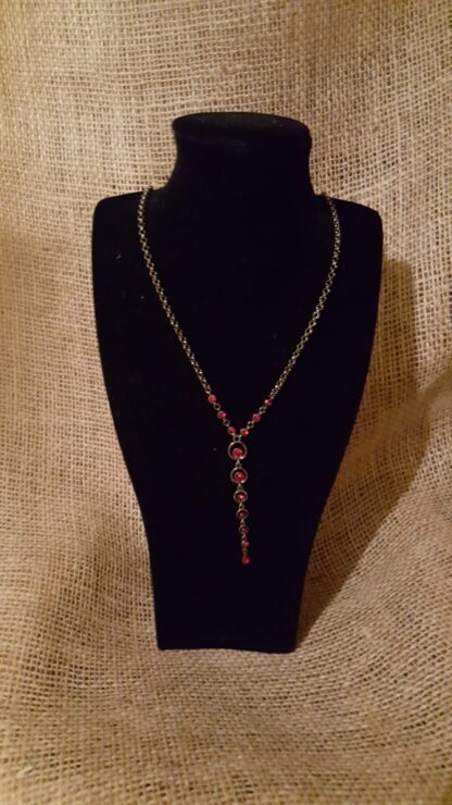 A necklace is displayed on a black display stand.