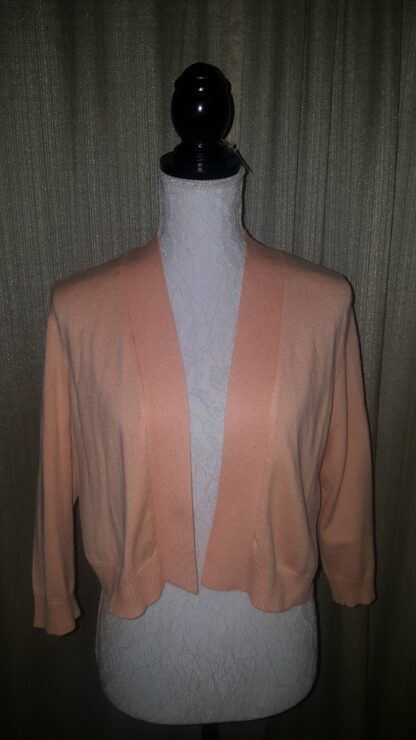 A pink cardigan is shown on display.
