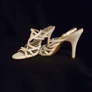 A pair of white high heels on black background.