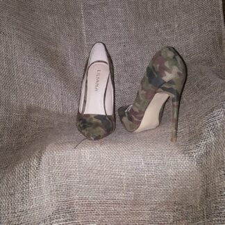 A pair of camouflage shoes sitting on top of a blanket.
