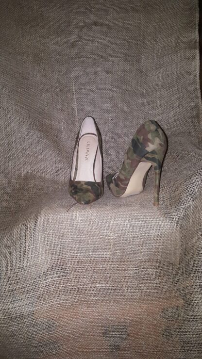 A pair of camouflage shoes sitting on top of a blanket.