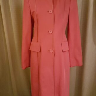 A pink coat is standing up against the wall