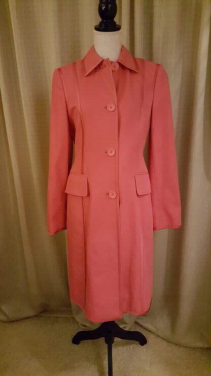 A pink coat is standing up against the wall