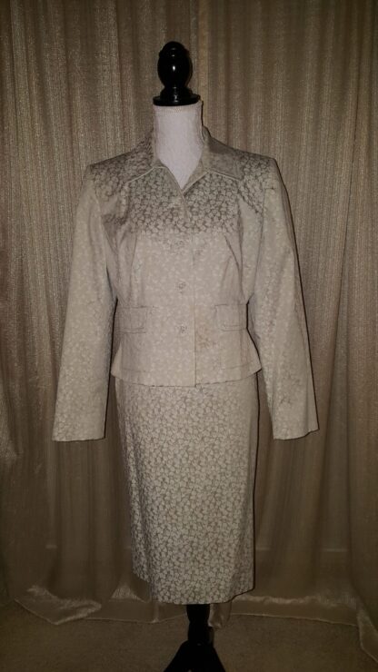 A woman 's suit is shown in front of a curtain.