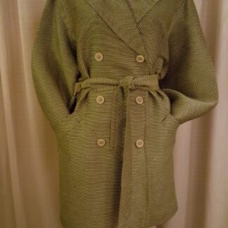 A coat that is on display in front of a curtain.