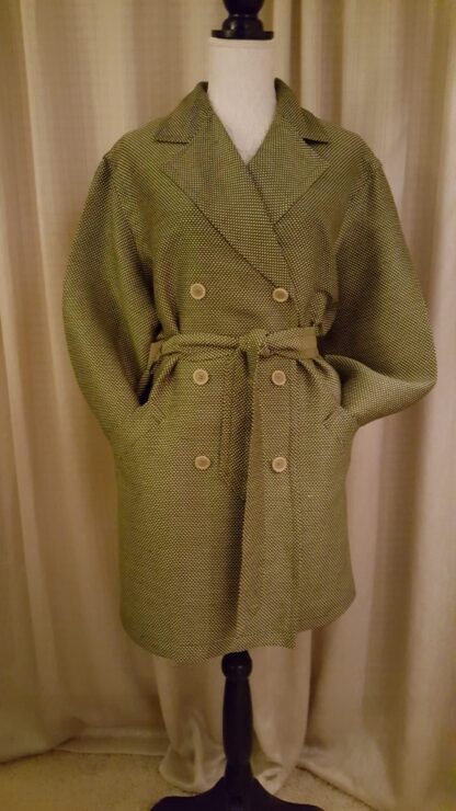 A coat that is on display in front of a curtain.