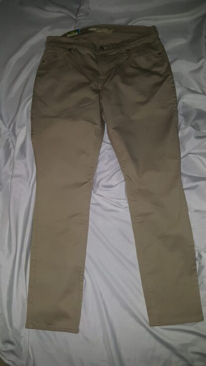 A pair of khaki pants sitting on top of a bed.