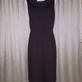 A black dress is hanging up in front of a curtain.