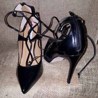 A pair of black high heels with laces on them.