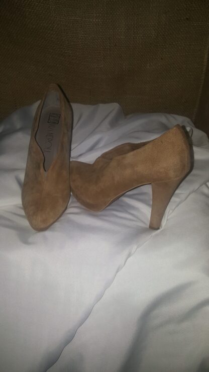A pair of brown shoes on top of a white blanket.