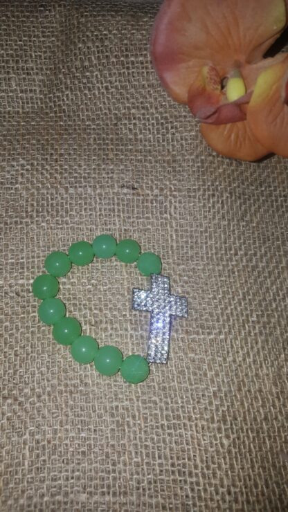 A green bead bracelet with a silver cross on it.