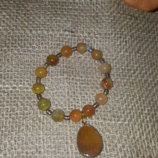 A bracelet with an orange stone and a large pendant.