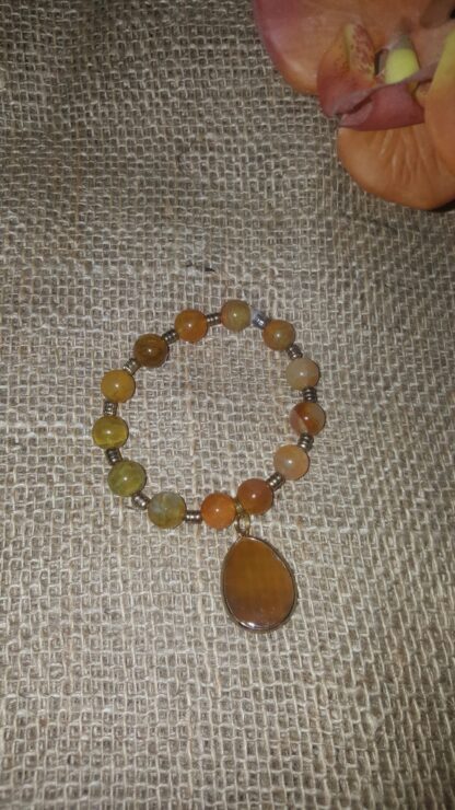 A bracelet with an orange stone and a large pendant.