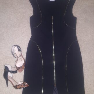 A black dress and shoes are on the floor.