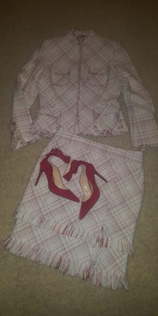 A pair of red shoes sitting on top of a skirt.