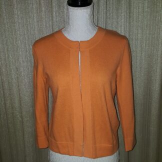 A woman wearing an orange sweater with three quarter sleeves.
